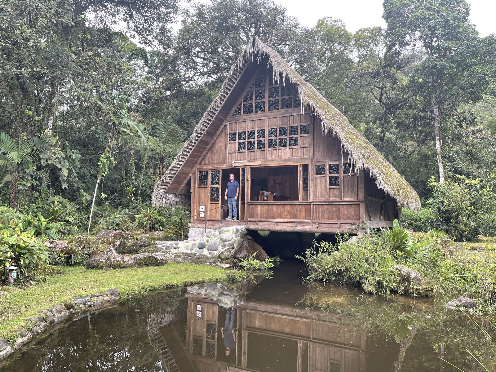 A thatched-roof lodge above a still pond in the Ecuadorian cloud forest